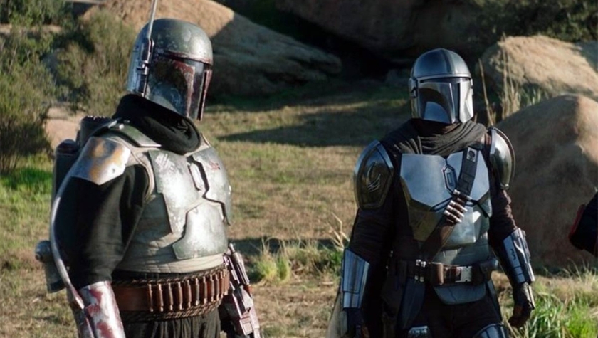 Boba Fett and Din Djarin standing together in The Mandalorian, both in full Mandalorian armor