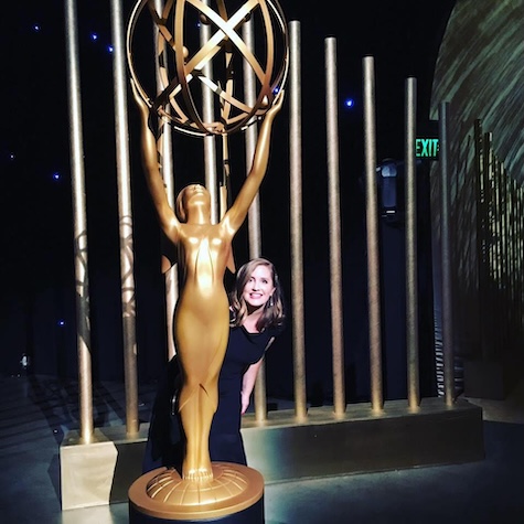 Alison Flierl posing next to a large Emmy Award statue