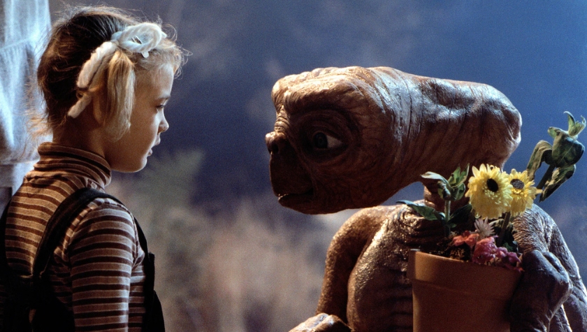 E.T. the Extra-Terrestrial holding a pot of flowers, face to face with Elliot's young sister Gertie