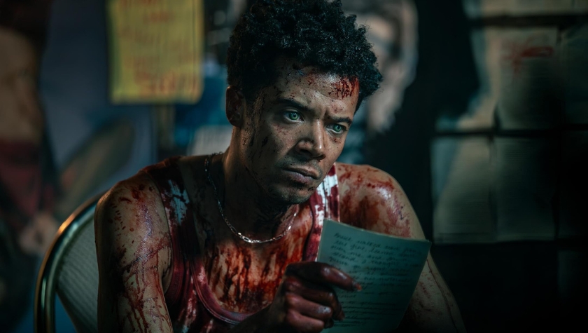 A blood-covered Jacob Anderson sits reading a handwritten note in a tense scene from AMC's The Vampire Lestat
